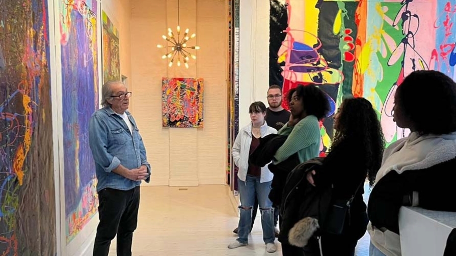 Students watch Peter Reginato discuss his abstract paintings.